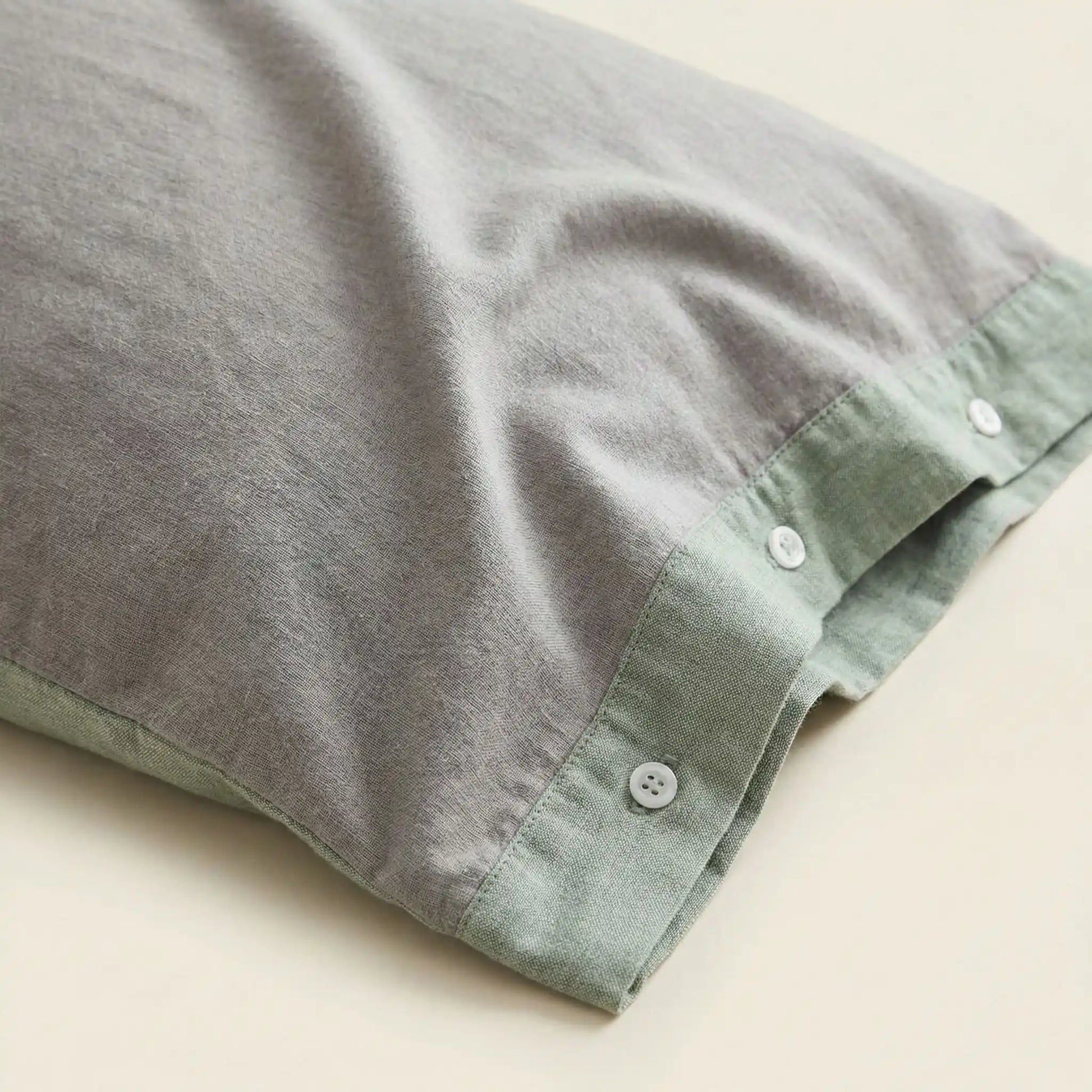 Détail de la texture d’une taie d’oreiller en gaze de coton gris sauge clair, tissu léger, respirant et délicatement froissé
