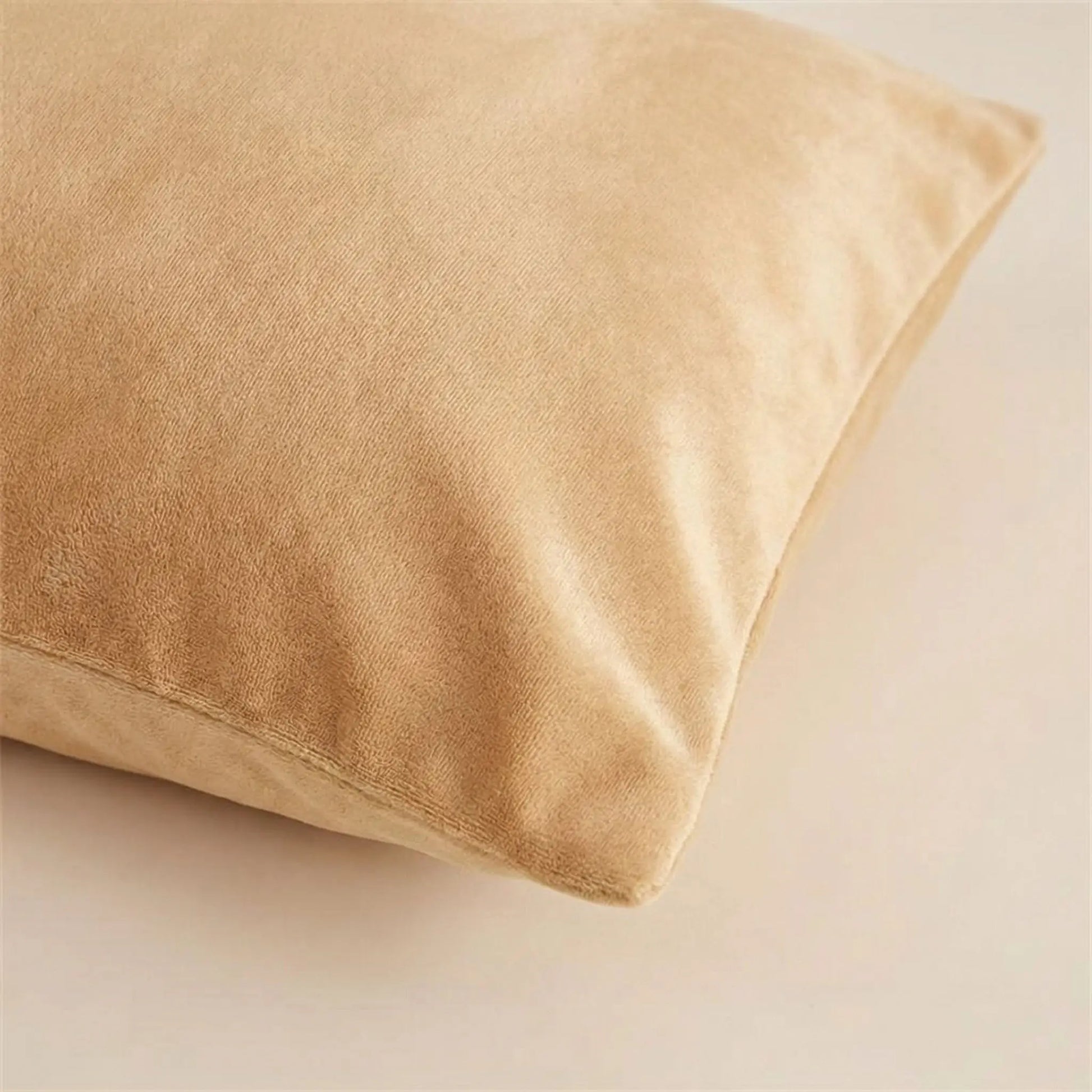 Détail de la texture d’une taie d’oreiller en velours camel, tissu doux, dense et subtilement lumineux