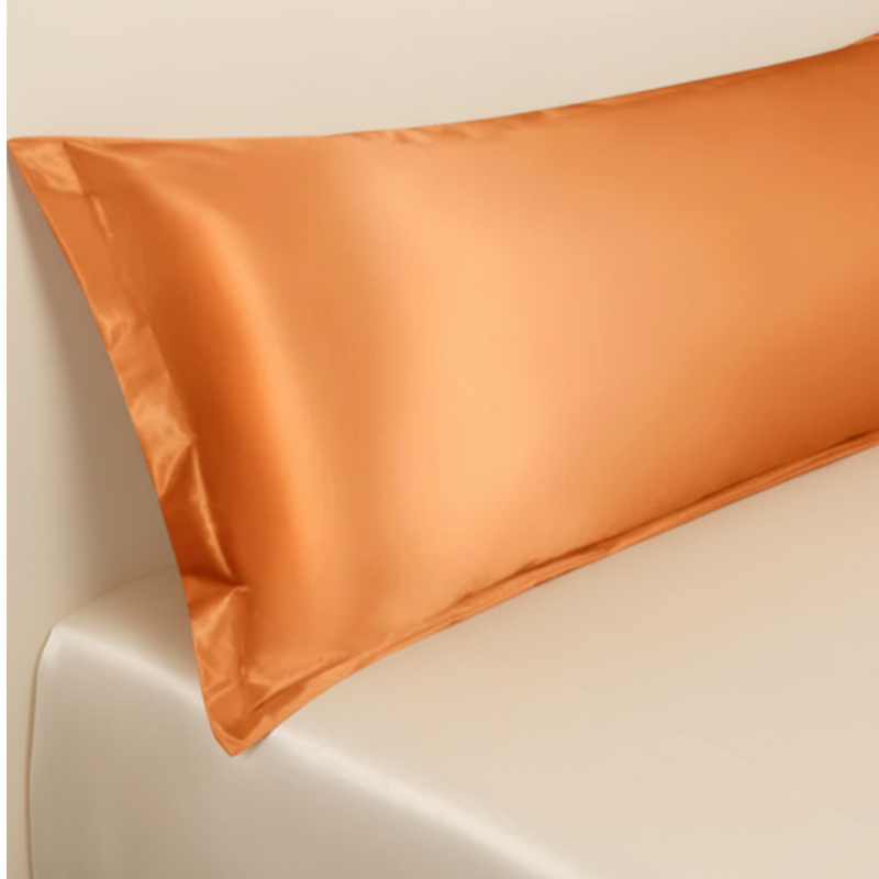 Détail de la texture d’une taie de traversin en satin orange avec finition lisse et brillante