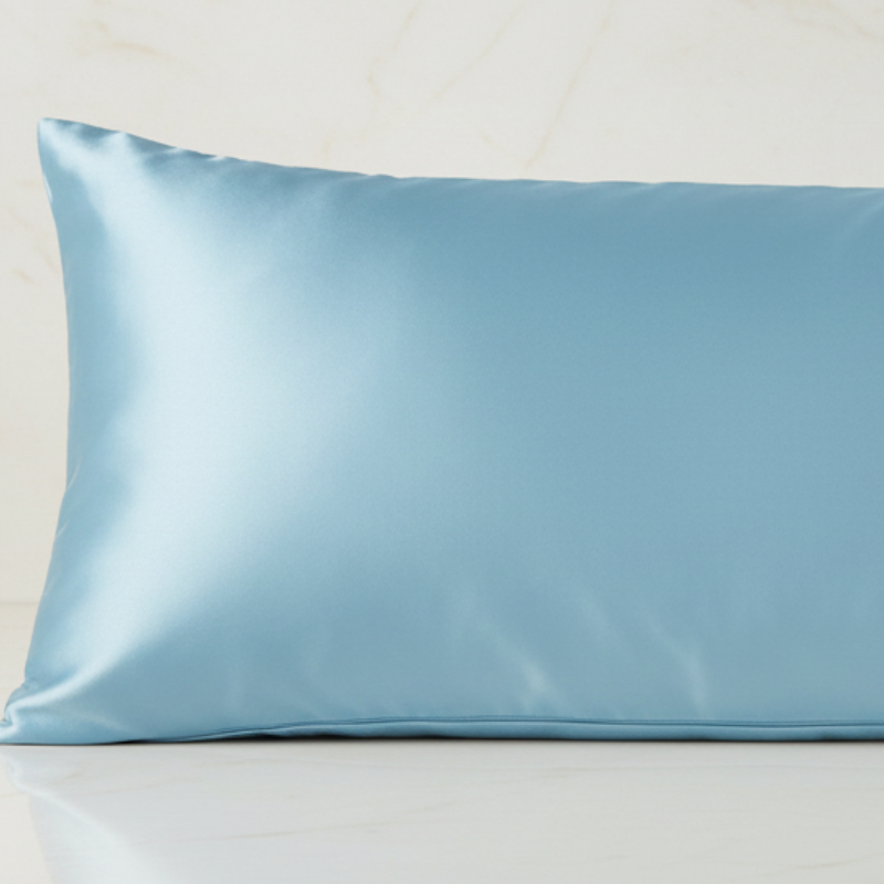 Détail de la texture d’une taie de traversin en soie de mûrier bleu ciel avec finition lisse et brillante