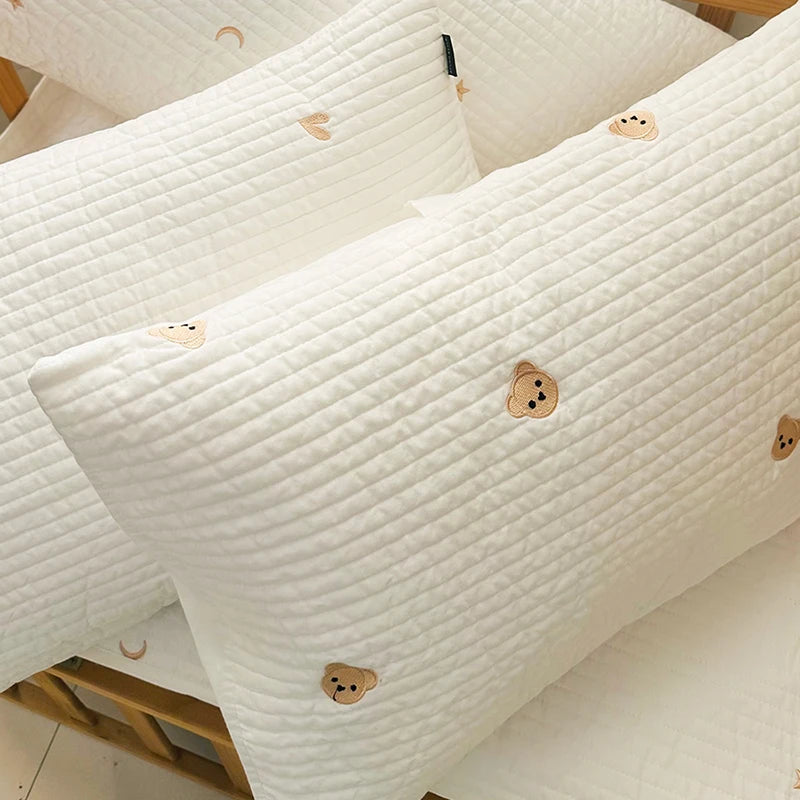 Focus sur Taie d’oreiller bébé en coton matelassé à motif oursons bruns présentée dans berceau