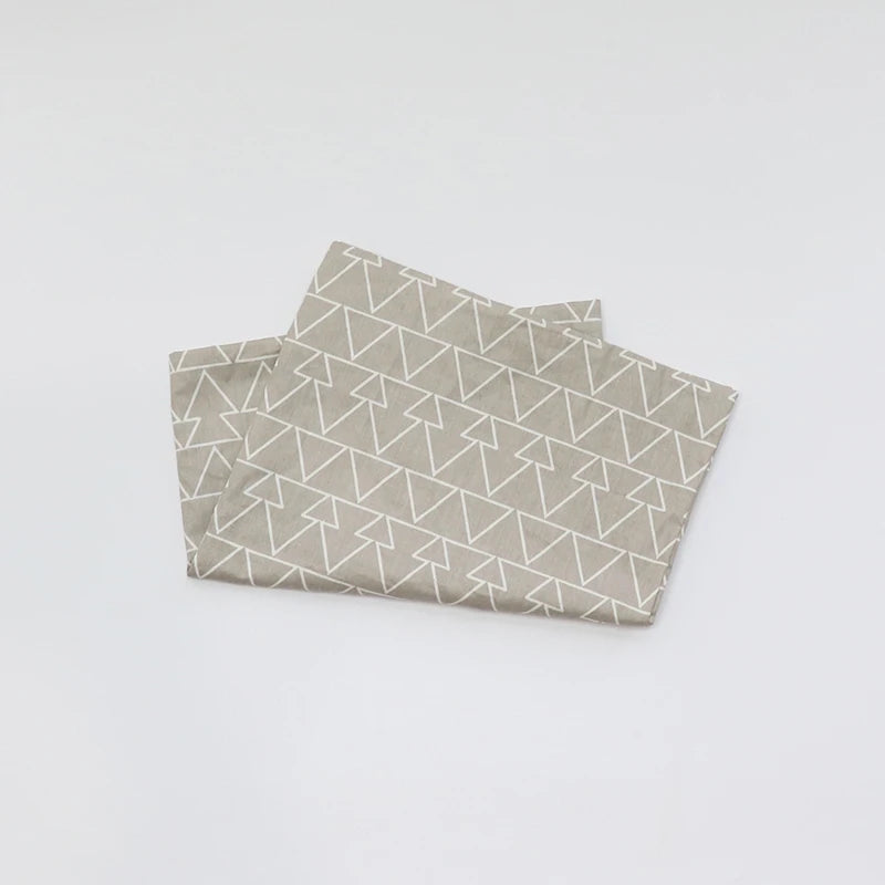 Taie d’oreiller bébé en coton à motif triangles pliée seule sur fond clair