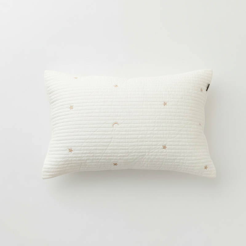 Taie d’oreiller bébé en coton matelassé à motif étoiles présentée seule sur fond clair