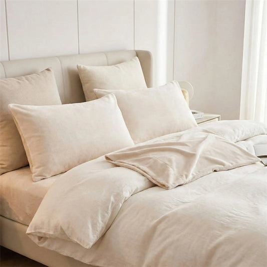 Taie d’oreiller en velours beige posée sur un lit en bois clair avec linge de lit ivoire, ambiance chaleureuse et cocooning