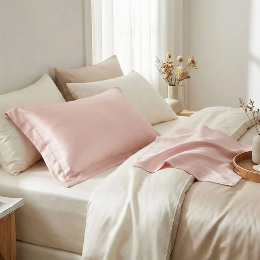 Taies d’oreiller INJOXFORD en soie de mûrier 30 mommes roses posées sur un lit en bois clair avec linge de lit blanc cassé ambiance lumineuse et naturelle