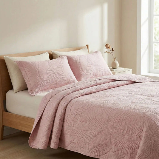 Taies d’oreiller en coton matelassé rose poudrée posées sur un lit en bois clair avec linge de lit rose
