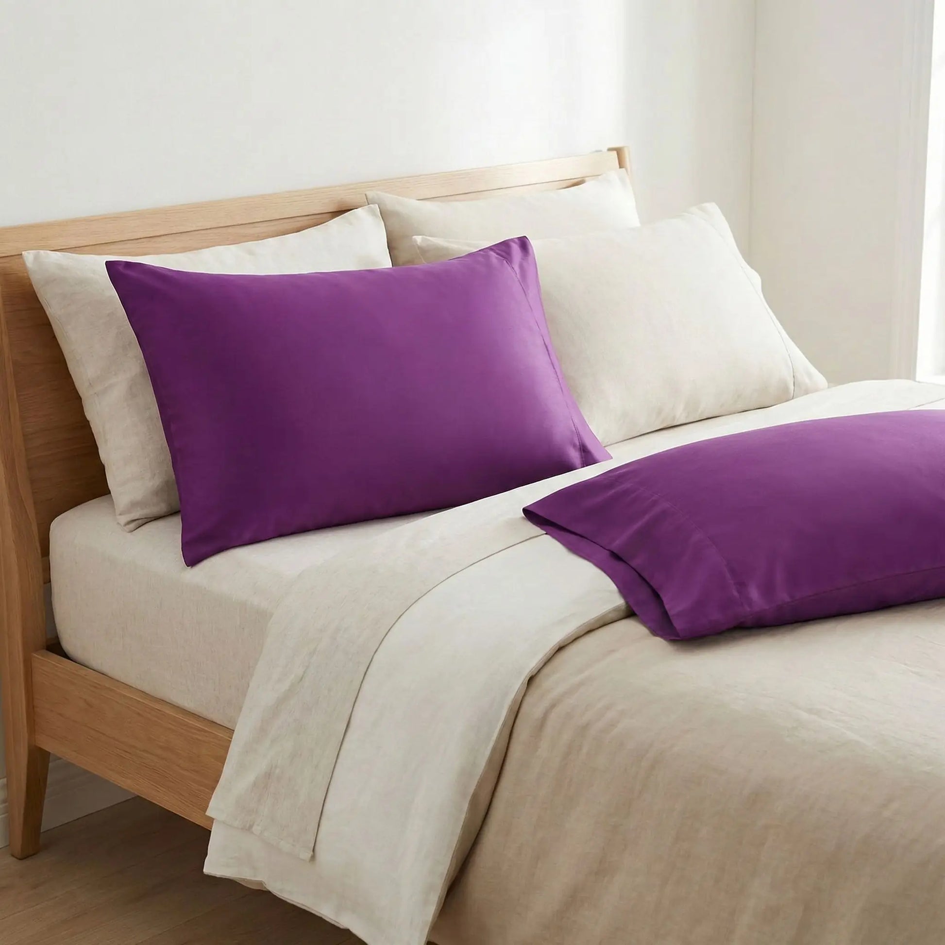 Taies d’oreiller en coton violet posées sur un lit en bois clair