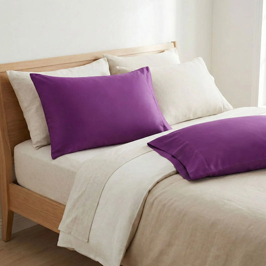 Taies d’oreiller en coton violet posées sur un lit en bois clair
