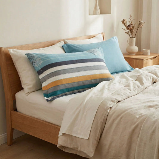 Taies d’oreiller en flanelle à rayures turquoise posées sur un lit en bois clair avec linge de lit blanc cassé