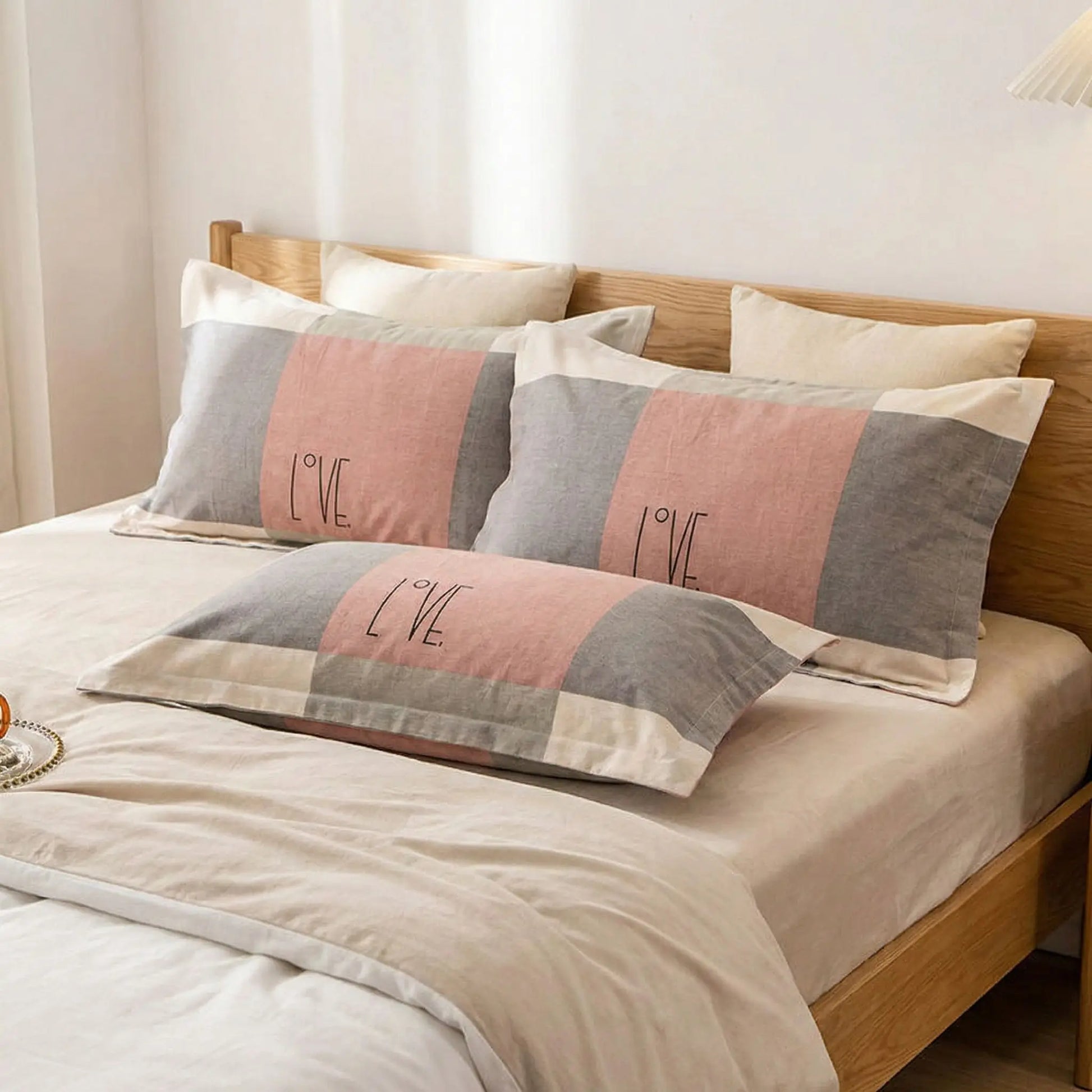 Taies d’oreiller en flanelle avec message Love posées sur un lit en bois clair avec linge de lit blanc cassé