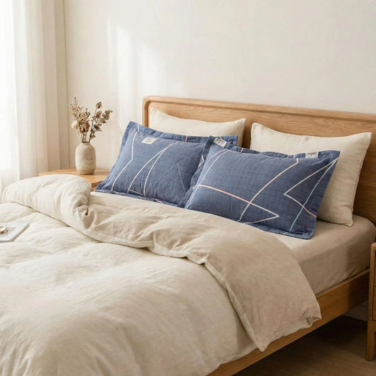 Taies d’oreiller en flanelle imprimée bleu océan posées sur un lit en bois clair avec linge de lit blanc cassé