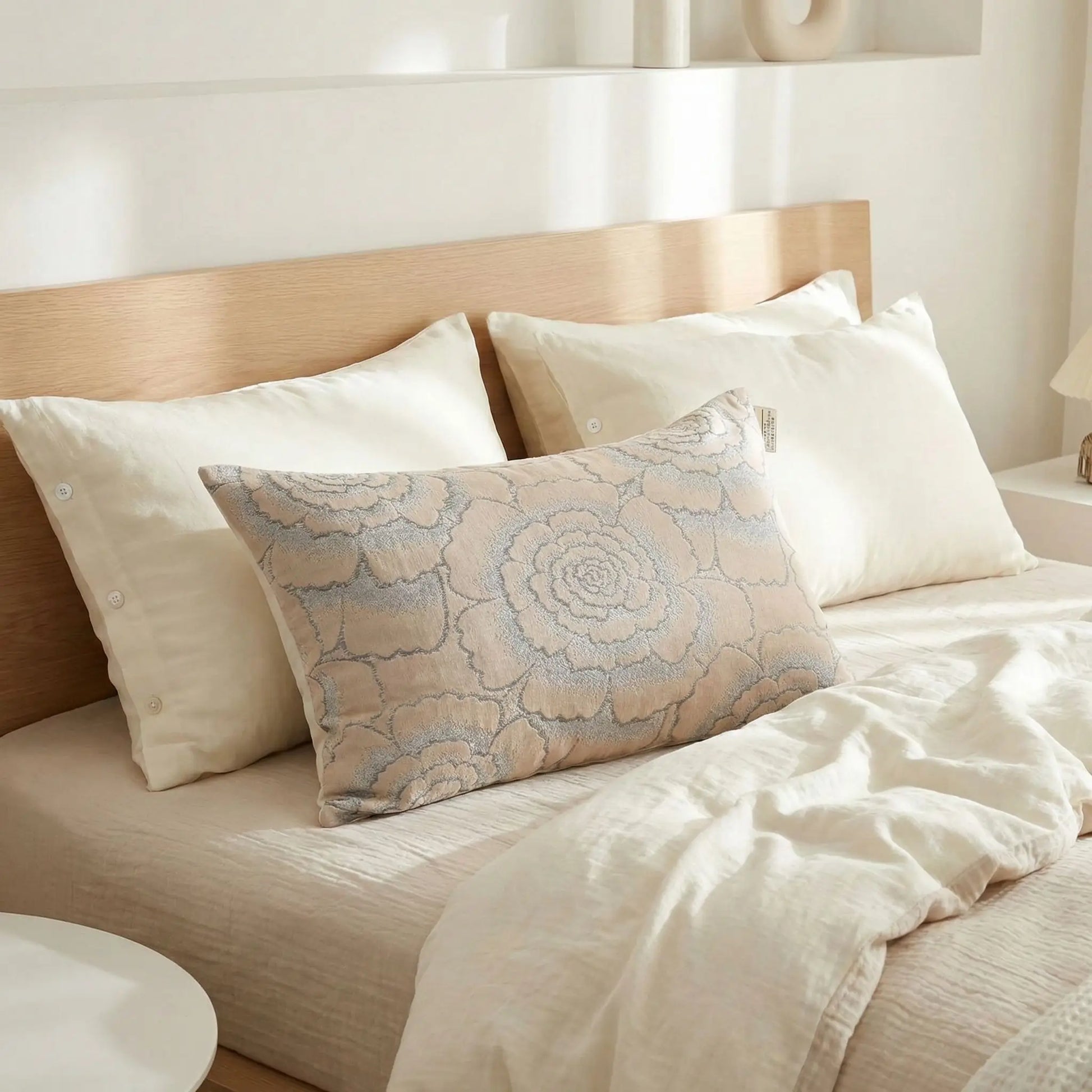 Taies d’oreiller en gaze de coton à motifs floraux posées sur un lit en bois clair