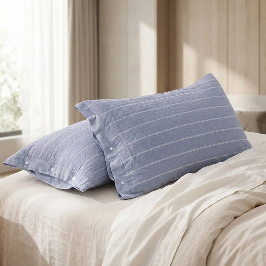 Taies d’oreiller en gaze de coton à rayures bleues posées sur un lit