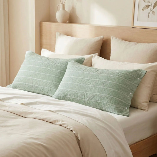 Taies d’oreiller en gaze de coton à rayures vertes posées sur un lit en bois clair