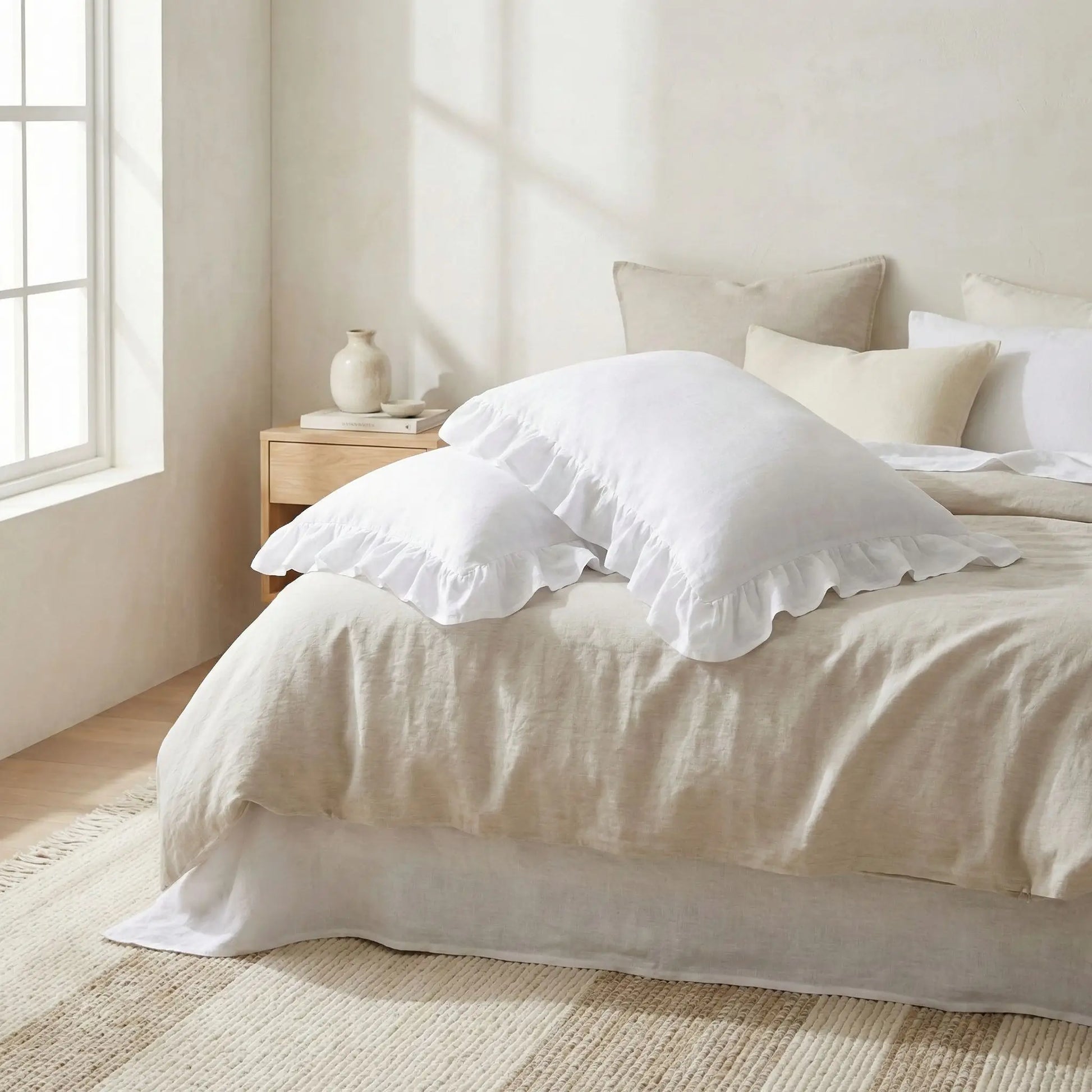 Taies d’oreiller en lin blanc à volants posées sur un lit moderne avec linge de lit blanc cassé