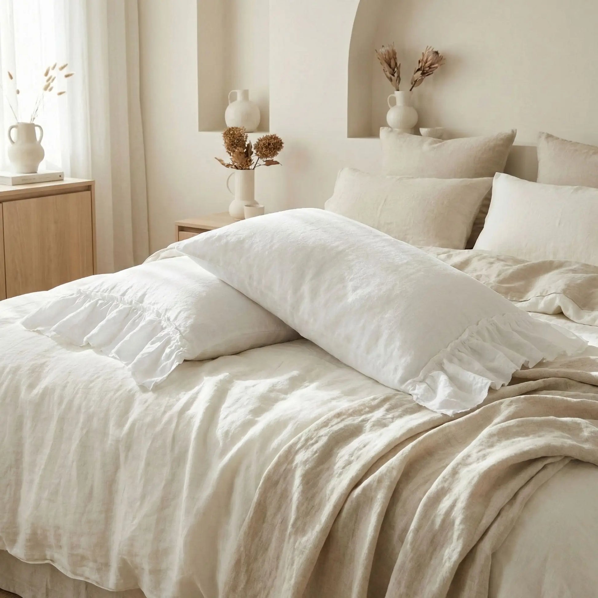 Taies d’oreiller en lin lavé blanc posées sur un lit moderne avec linge de lit blanc cassé