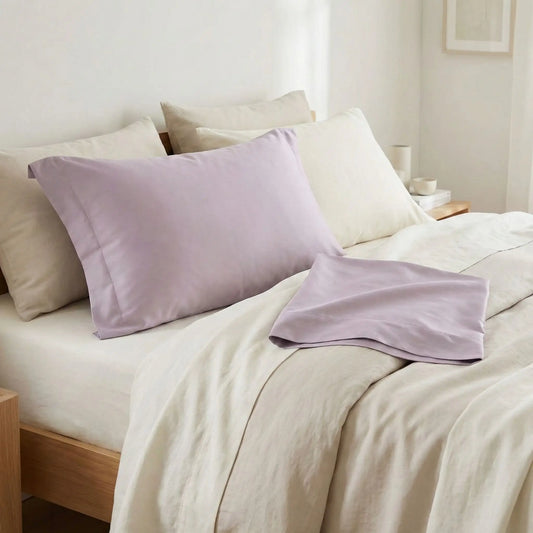 Taies d’oreiller en satin de coton violet grisée posées sur un lit moderne