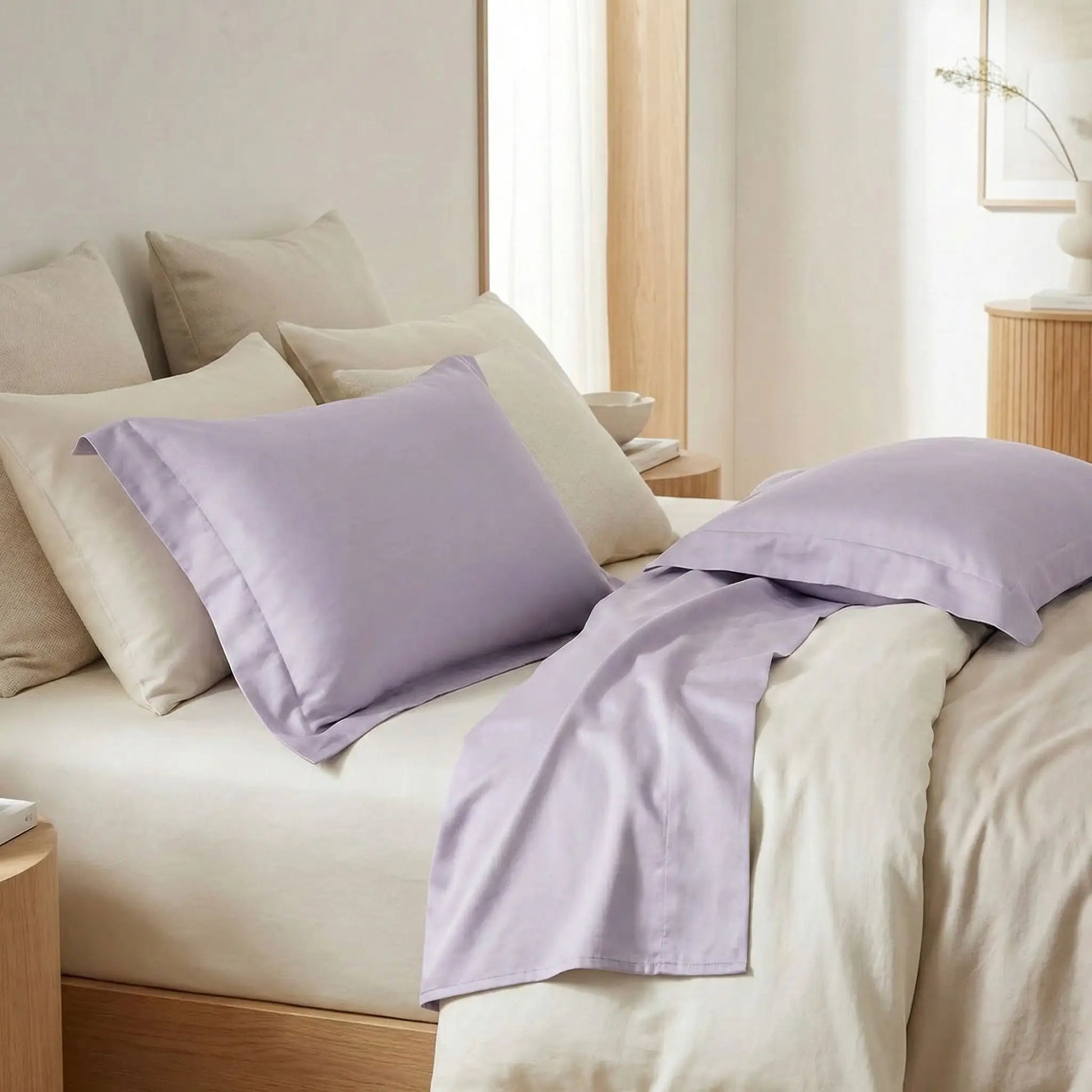 Taies d’oreiller en satin de coton violet lilas posées sur un lit moderne